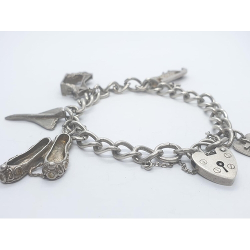 408 - Silver charm bracelet with 6 charms and heart padlock, weight 28.5g a and 16cm long approx