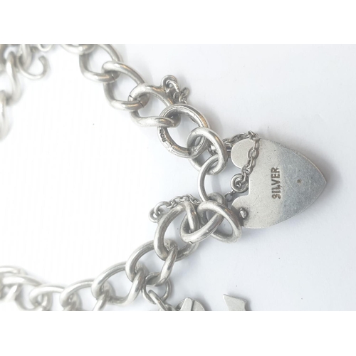 408 - Silver charm bracelet with 6 charms and heart padlock, weight 28.5g a and 16cm long approx