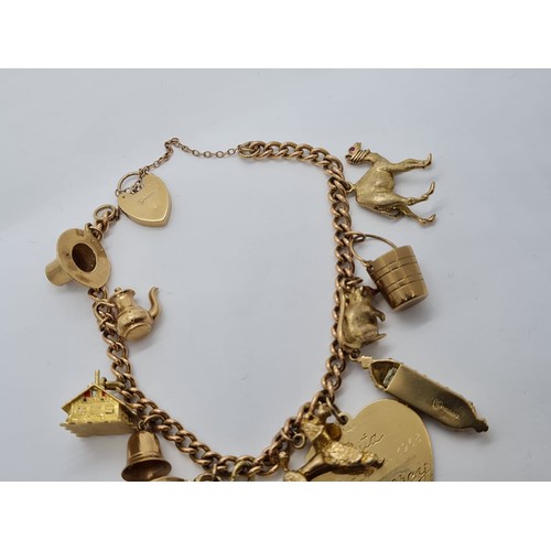 569 - 9ct gold vintage charm bracelet with 12 charms weight 53.3gram 18cm long with heart padlock.