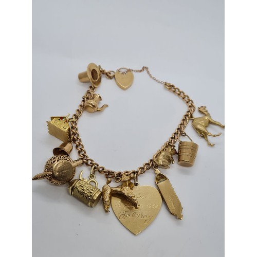 569 - 9ct gold vintage charm bracelet with 12 charms weight 53.3gram 18cm long with heart padlock.