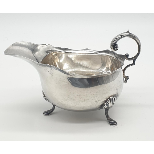 165 - Vintage silver sauce boat having scalloped rim and scroll handle, standing on three cabriole legs wi... 