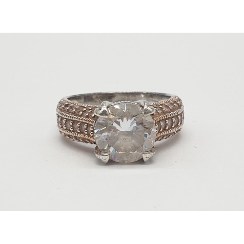 476 - Silver ring having rose coloured shoulders encrusted with gems and a large faceted clear stone in fo... 