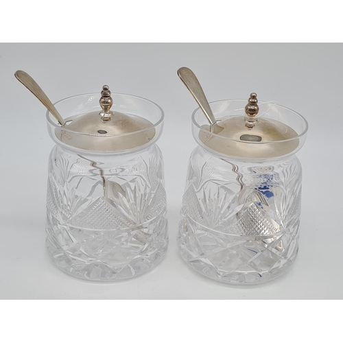 369 - Pair of cut glass silver lidded condiment jars with silver lid and silver spoon. 10cm high 483gm eac... 