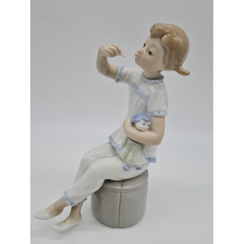 375 - Lladro girl with doll eating. 19cm tall.