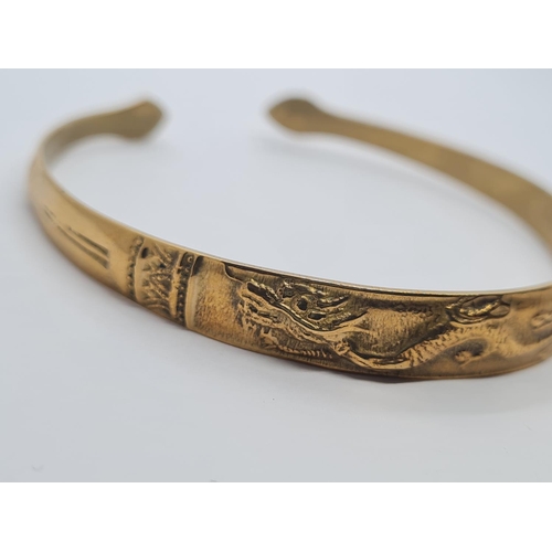 405 - Vintage yellow metal bangle, believed to be oriental with dragon motif. 14.5g.