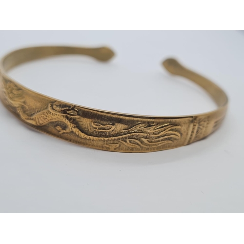 405 - Vintage yellow metal bangle, believed to be oriental with dragon motif. 14.5g.