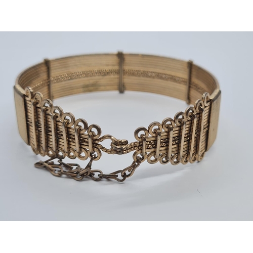 427 - A Victorian yellow metal gated bangle with safety chain. 26.9g.