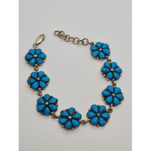 493 - A silver and turquoise bracelet in floral form. 19.6g, 16cm.