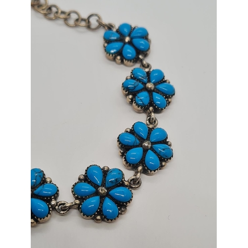 493 - A silver and turquoise bracelet in floral form. 19.6g, 16cm.