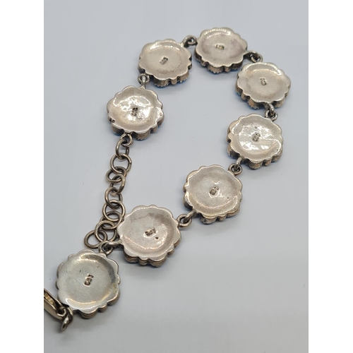 493 - A silver and turquoise bracelet in floral form. 19.6g, 16cm.