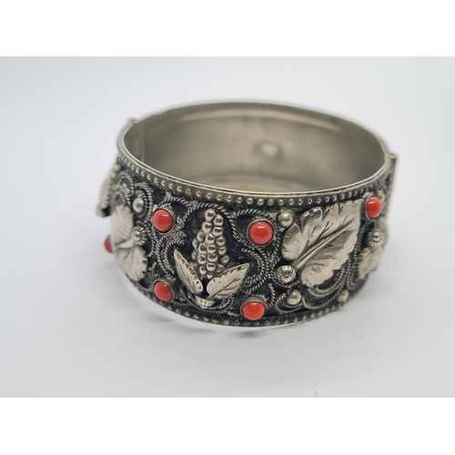 495 - A vintage Italian white metal bangle with cornellean and floral design. 43.5g.