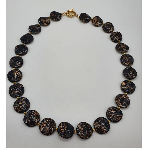 163 - A 60’s black and gold coloured necklace, bracelet and earrings set in a presentation box. Necklace l... 