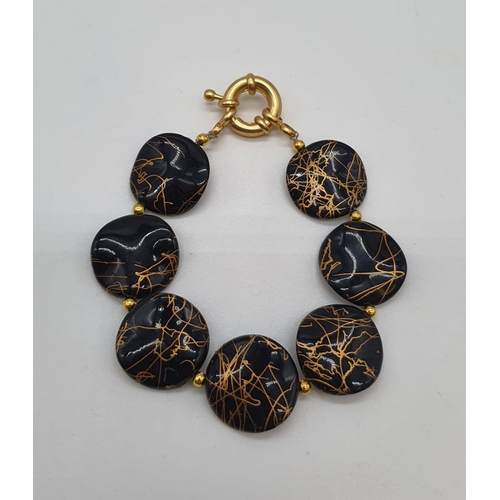 163 - A 60’s black and gold coloured necklace, bracelet and earrings set in a presentation box. Necklace l... 