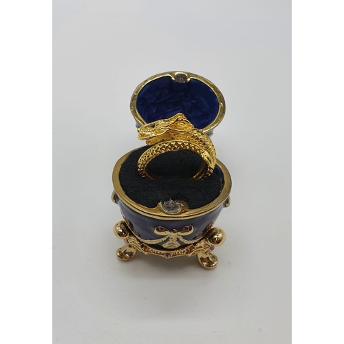 60 - A yellow metal (untested) Chinese dragon ring presented in Faberge style egg.