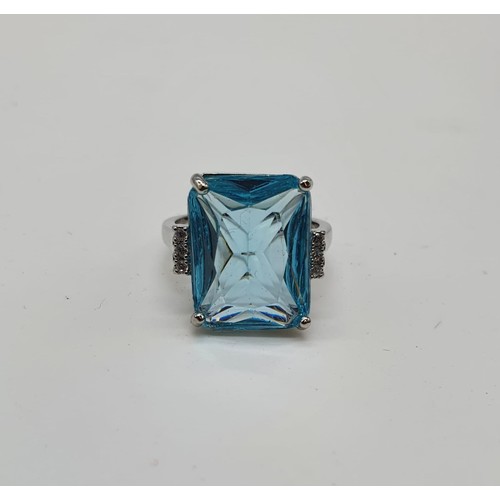 130 - A silver (stamped 925) ring with a central aqua marine stone (emerald cut) and six small sapphires o... 