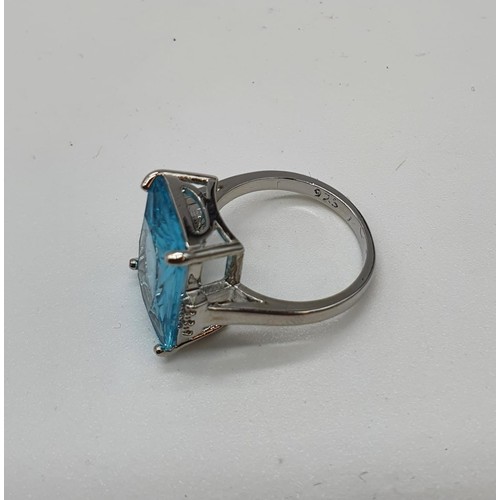 130 - A silver (stamped 925) ring with a central aqua marine stone (emerald cut) and six small sapphires o... 