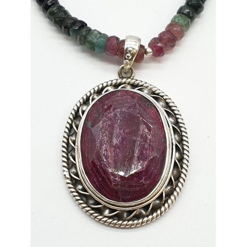 166 - A single strand tourmaline necklace with with ruby pendant in sterling silver. Length 27cm, 45.82g.