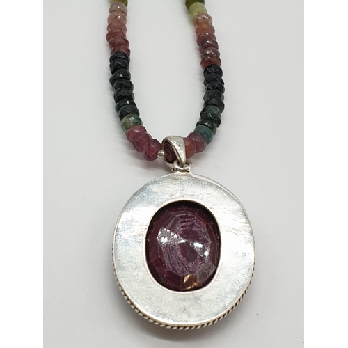 166 - A single strand tourmaline necklace with with ruby pendant in sterling silver. Length 27cm, 45.82g.