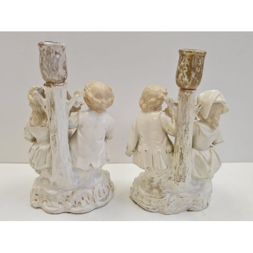 72 - Pair of ceramic candlesticks with figures in Victorian themed fashion. Height 19cm.