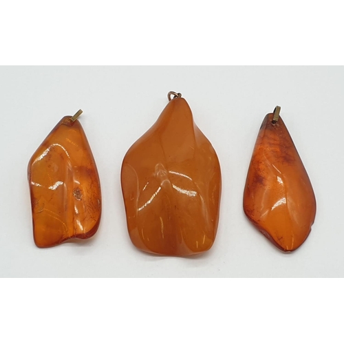 184 - Three amber pendants.