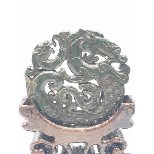 102 - A Chinese, hand carved on both sides and pierced, dark green jade amulet, representing mythical beas... 