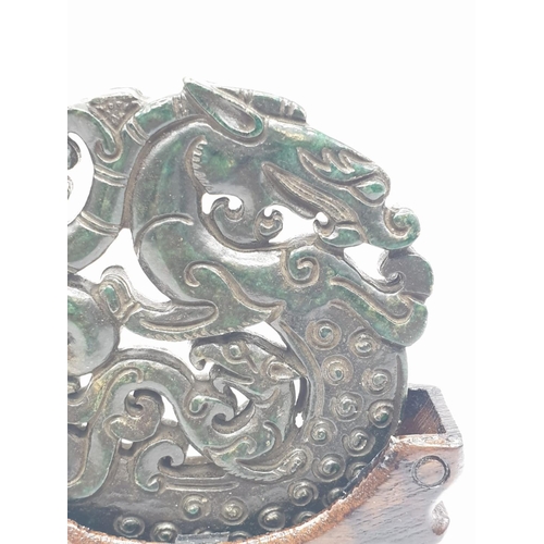 102 - A Chinese, hand carved on both sides and pierced, dark green jade amulet, representing mythical beas... 