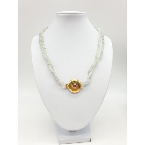 373 - An aquamarine necklace with a gold plated silver clasp, tourmaline stone at the centre of clasp. Som... 