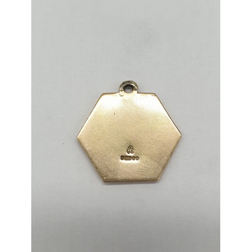 261 - 9ct gold hexagonal charm/pendant. Featuring man and child crossing water. length 2cm. Weight 2.95g