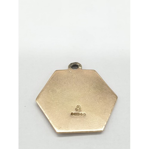 261 - 9ct gold hexagonal charm/pendant. Featuring man and child crossing water. length 2cm. Weight 2.95g