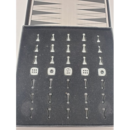 187 - A mini magnetic backgammon board with pieces. 14cm x 14cm.