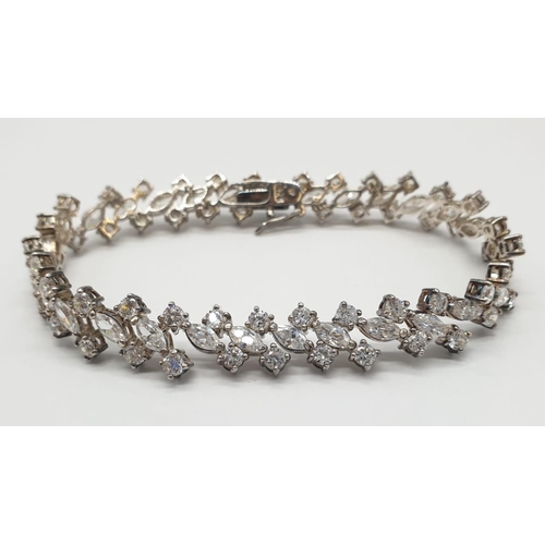 106 - Silver tennis bracelet with stones set in trilogy form along the length of the bracelet. Bracelet le... 