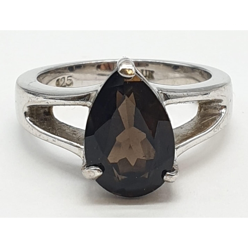 13 - Silver Ring, with brown topaz pear shaped stone in silver claw mount. Pierced shoulders and clear ma... 