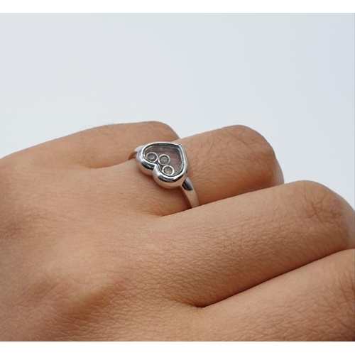 144 - 9ct white gold heart ring with 3 small moving diamonds to centre. Small crack to back. Size J. Weigh... 