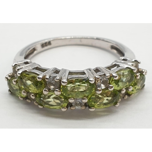 434 - Silver and peridot ring having peridot and clear topaz stones to top set in half hoop form. 925 silv... 