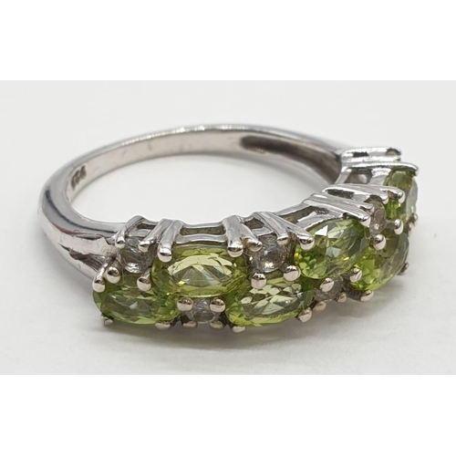 434 - Silver and peridot ring having peridot and clear topaz stones to top set in half hoop form. 925 silv... 