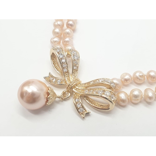 64 - A two rows of pink pearls necklace and earrings set in a presentation box. Necklace length: 44cm, ea... 