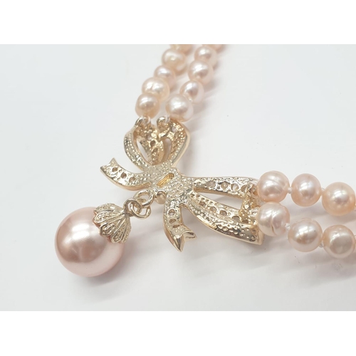 64 - A two rows of pink pearls necklace and earrings set in a presentation box. Necklace length: 44cm, ea... 