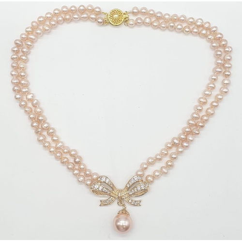 64 - A two rows of pink pearls necklace and earrings set in a presentation box. Necklace length: 44cm, ea... 