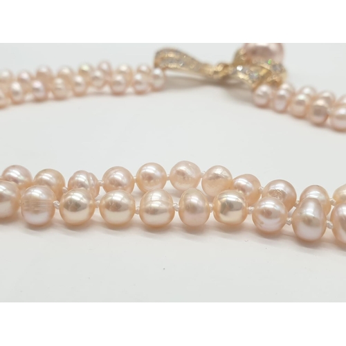 64 - A two rows of pink pearls necklace and earrings set in a presentation box. Necklace length: 44cm, ea... 