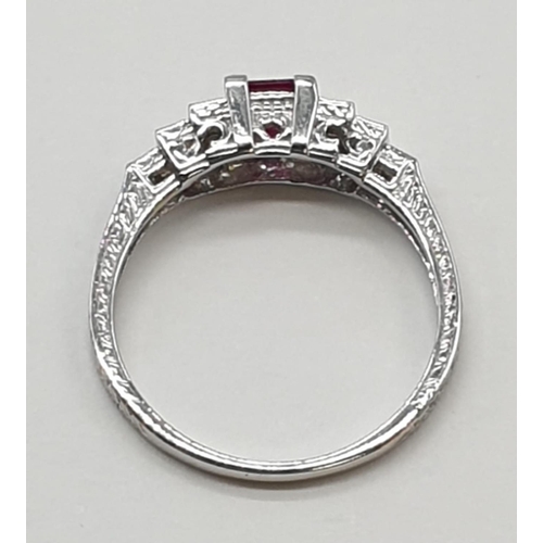 113 - An art deco style ladies 18ct white gold diamond and ruby (emerald cut) ring. Size N.0.3ct ruby. Tot... 