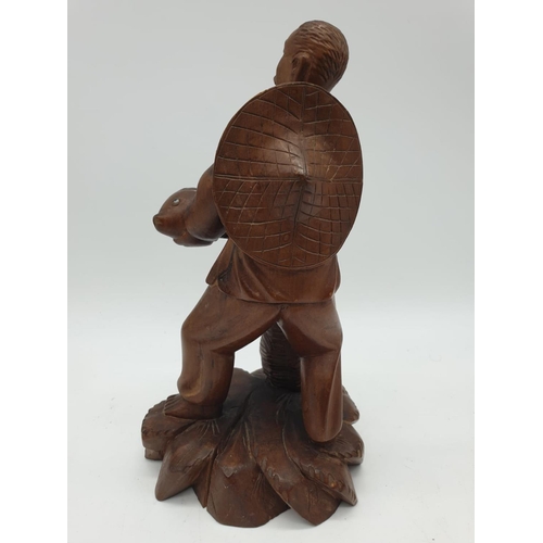 247 - A Chinese wooden hand Carved Fisherman holding a large fish, 22cm tall