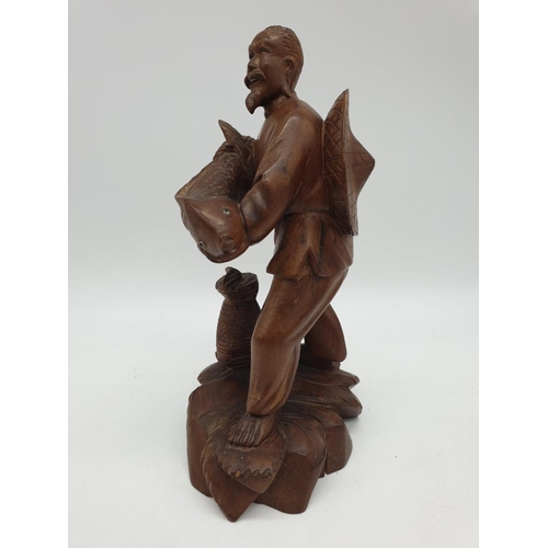 247 - A Chinese wooden hand Carved Fisherman holding a large fish, 22cm tall