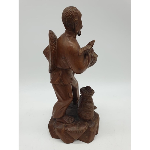 247 - A Chinese wooden hand Carved Fisherman holding a large fish, 22cm tall