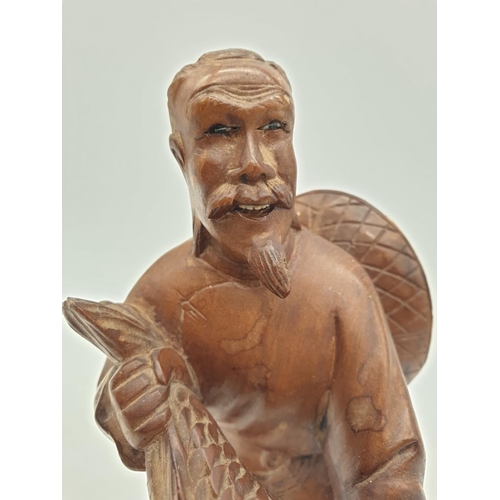 247 - A Chinese wooden hand Carved Fisherman holding a large fish, 22cm tall