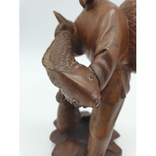 247 - A Chinese wooden hand Carved Fisherman holding a large fish, 22cm tall