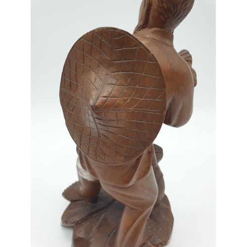 247 - A Chinese wooden hand Carved Fisherman holding a large fish, 22cm tall