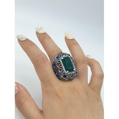 308 - A multi coloured silver ring with jade centre stone. 22.7g in weight. Size L.