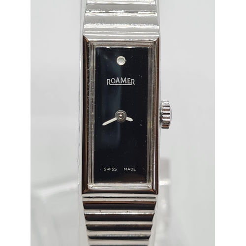 524 - Vintage ladies Roamer wristwatch. Square black face with white hands having silver chrome strap. Man... 