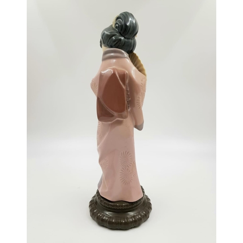 192 - A Lladro porcelain figurine of a timid Japanese Geisha with fan. Very good condition. 30cm high.