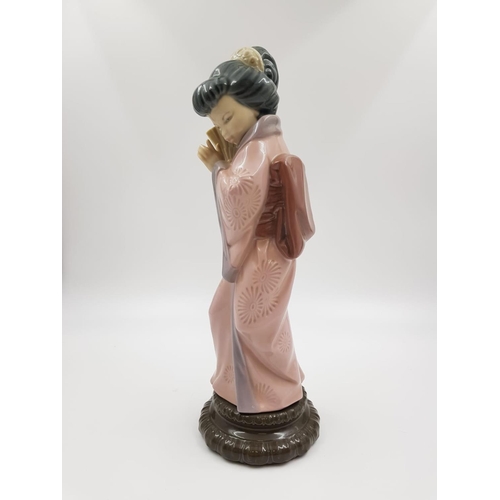 192 - A Lladro porcelain figurine of a timid Japanese Geisha with fan. Very good condition. 30cm high.